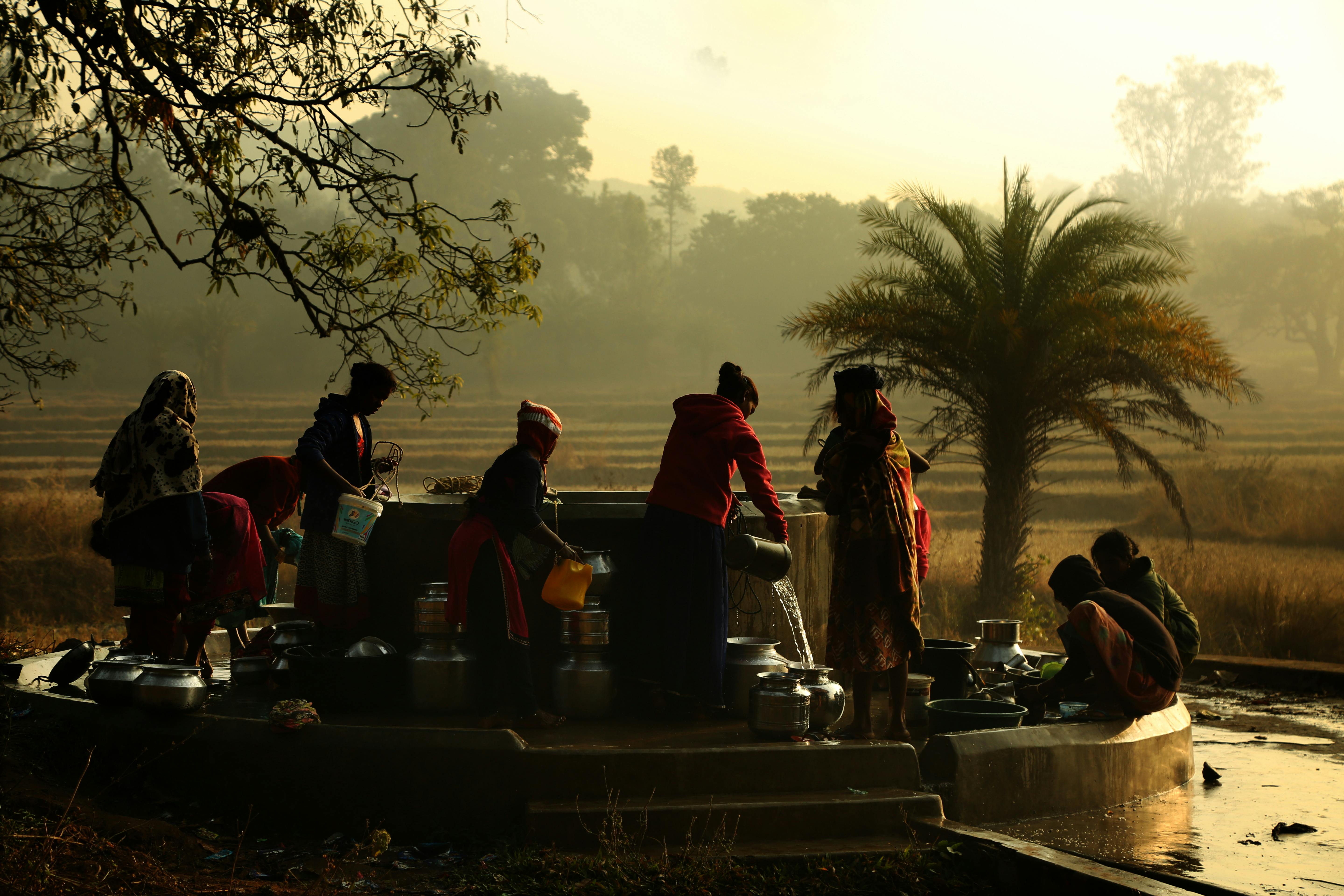 A group of women collecting water from a fountain at dawn in Araku Valley, India.