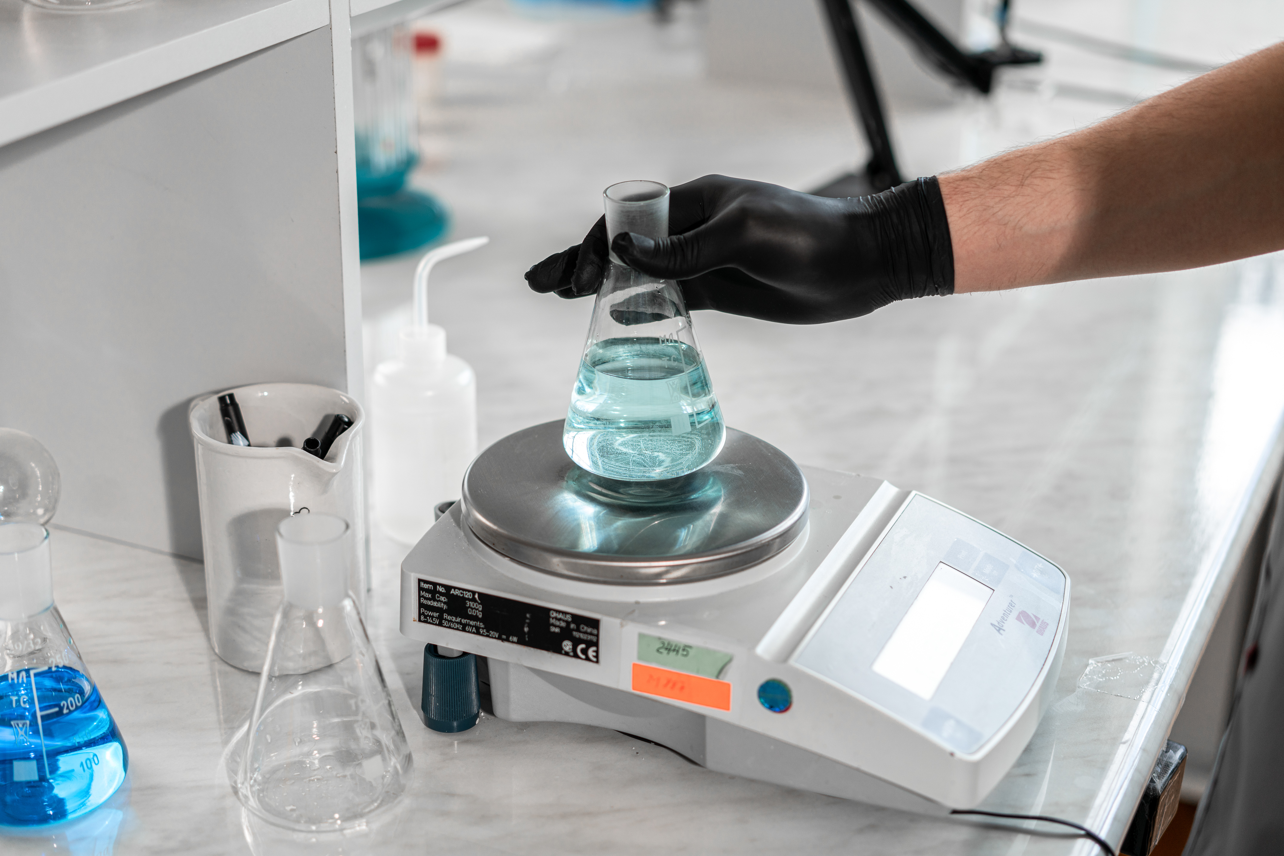 Project Categories A scientist handling a liquid-filled flask on a laboratory scale for precise measurement.
